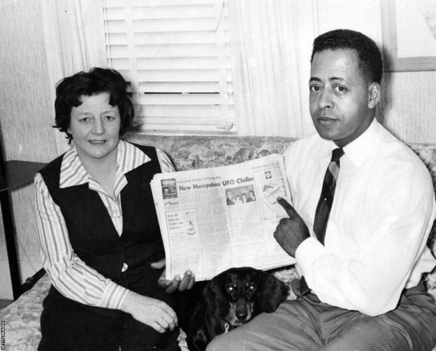 Betty and Barney Hill hold up a newspaper featuring their story