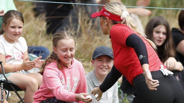 Olivia Mehaffey gifts a golf ball to a fan