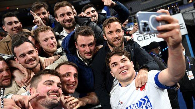 Le demi de mêlée et capitaine français Antoine Dupont, à droite, pose pour un selfie avec les fans