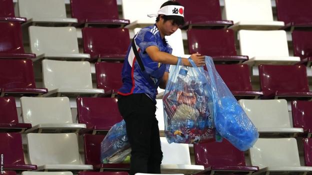 A Japan fan holding bags full of rubbish