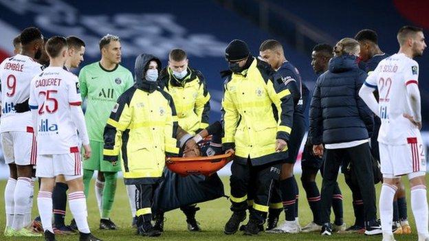 Players watch as Paris St-Germain forward Neymar is carried off on a stretcher in a match against Lyon