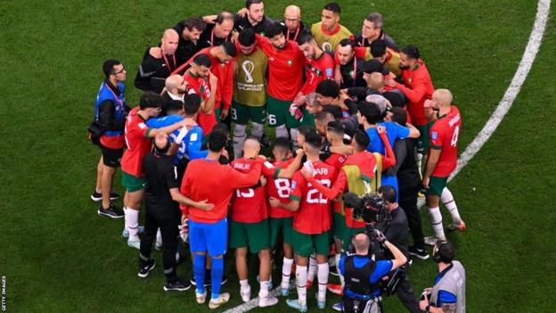 Morocco players in a huddle after the semi-final defeat by France