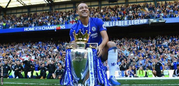 John Terry with the Premier League trophy at Stamford Bridge in from of the banner: "Captain. Leader. Legend."