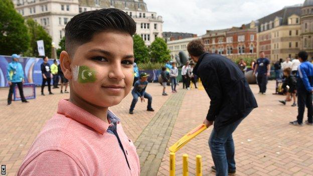 A South Asian boy joining in a game of street cricket