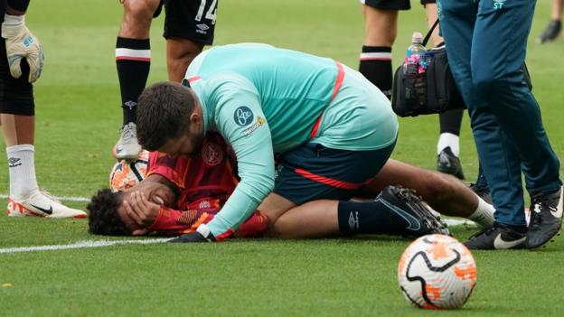 Kevin Schade on the pitch in pain after pulling up injured