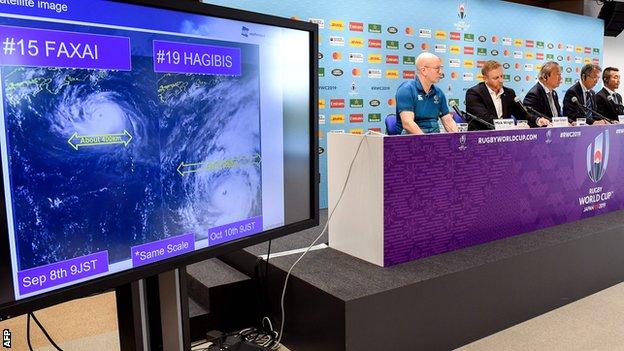 Rugby World Cup organisers brief the media as a screen shows the path of the approaching typhoon