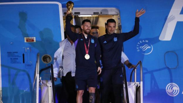 Lionel Messi steps out of a plane with the World Cup trophy