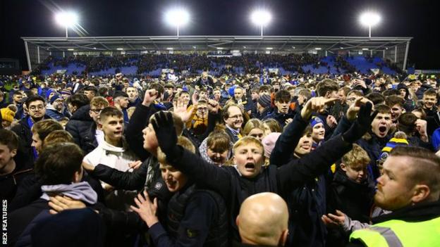 Shrewsbury fans celebrated on the pitch after the League One club earned a replay against Liverpool at Anfield