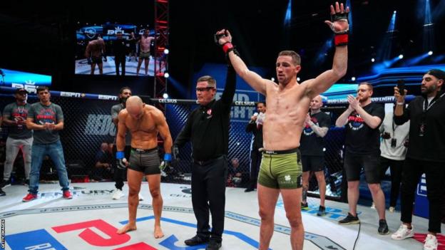 The referee lifts Brendan Loughnane right hand as he celebrates defeating Marlon Moraes