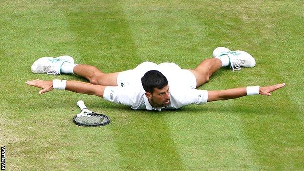Novak Djokovic liegt mit ausgestreckten Armen und Beinen auf der Brust, nachdem er bei seinem Viertelfinalsieg gegen Jannik Sinner einen Punkt geholt hat
