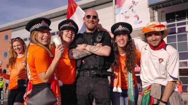 Netherlands and Portugal fans pose with a police officer outside Le Sports Village ahead of their Euro 2022 game