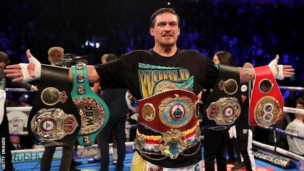 Oleksandr Usyk celebrates with all four world cruiserweight title belts after beating Tony Bellew