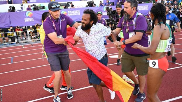 Protestor with Tigray flag is handled by security on the track in Eugene