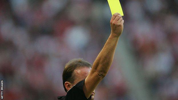 A referee showing a yellow card