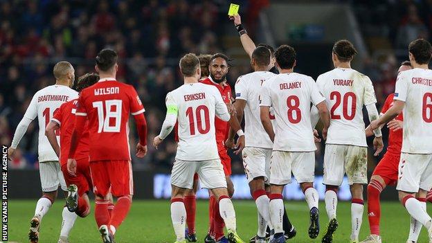 Wales defender Ethan Ampadu is shown a yellow card against Denmark