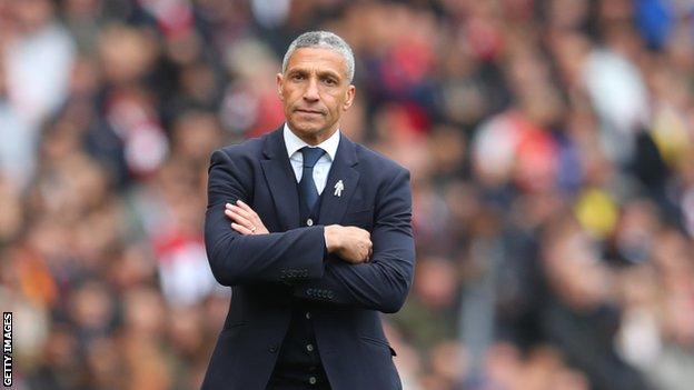 Chris Hughton stands with his arms folded