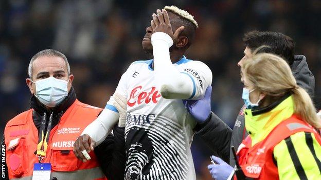 Napoli and Nigeria striker Victor Osimhen being led off the pitch by medics