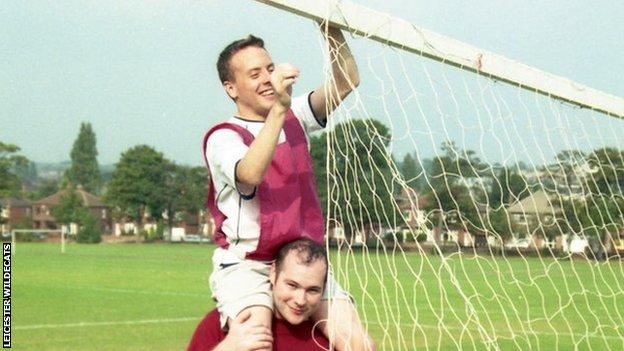 Two Leicester Wildecats players attach a football net to a goal frame