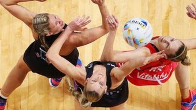 England and New Zealand netball players jump for the ball.