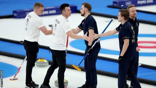 Les curleurs de Grande-Bretagne et de Suède se serrent la main après la finale olympique