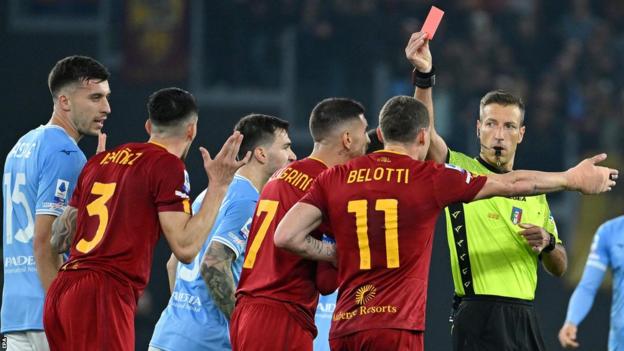 Referee Davide Masse shows a red card to Roma's Roger Ibanez during the Derby della Capitale