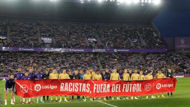 Real Valladolid and Barcelona players hold the anti-racist flag