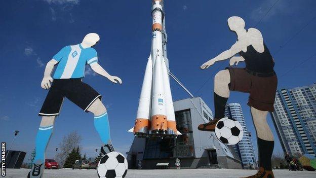 Two cut-out footballers by the Soyuz carrier rocket monument in Samara