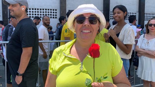 Pele fan Beatrice holding a rose as she queues to see Pele lying in state