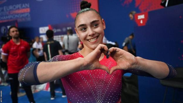 jessica gadirova makes a heart sign with her hands