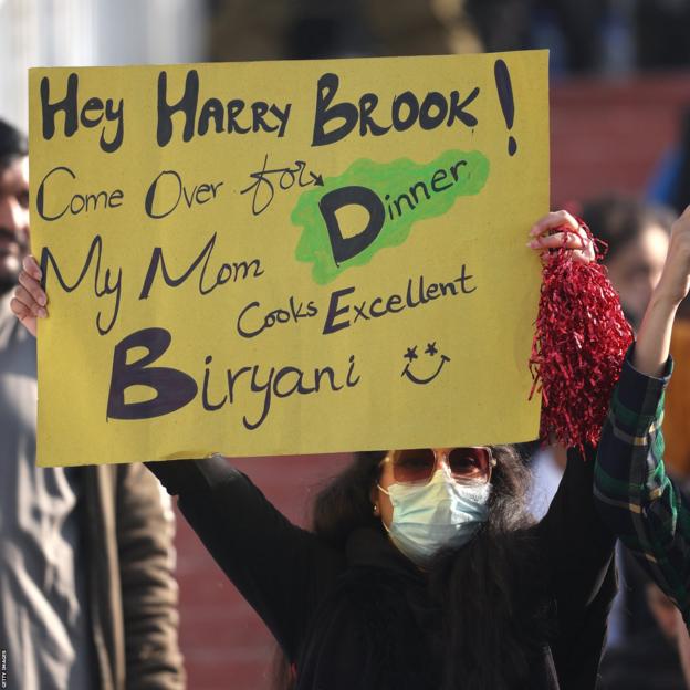 Een Pakistaanse fan houdt een spandoek vast waarop staat: "Hé Harry Brook!  Kom eten.  Mijn moeder kookt uitstekende biryani."