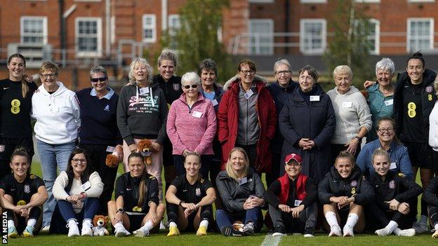 England players and former Lionesses pose for a group photograph during a training session