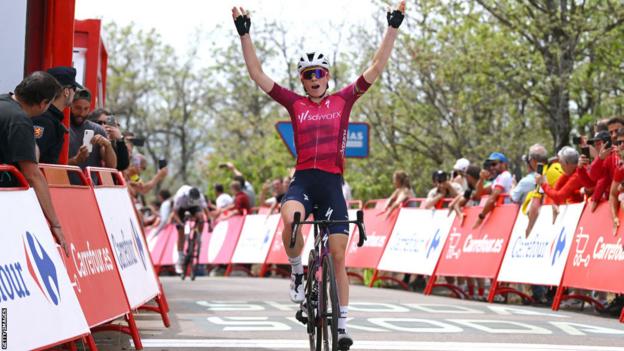 Demi Vollering raises her arms as she crosses the finish line