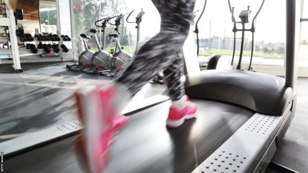 A woman runs on a treadmill in the gym