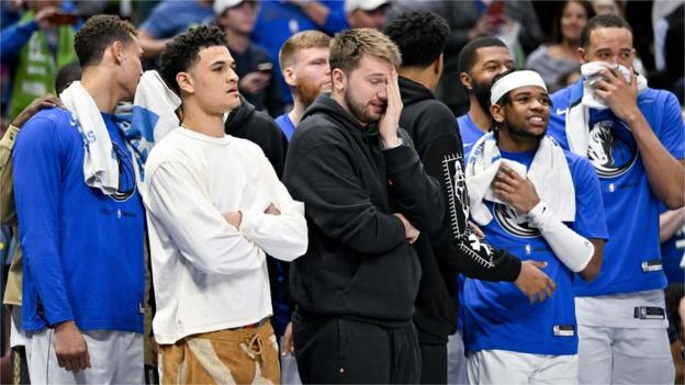 Luka Doncic covering his face with his hand as he watches the rest Dallas Mavericks v Chicago Bulls game courtside after he was taken off during the first quarter
