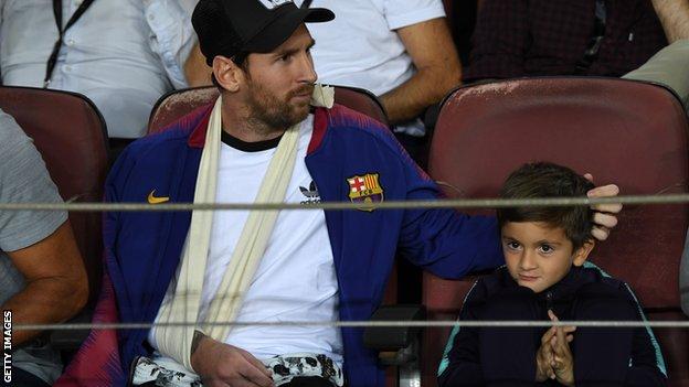 Lionel Messi watching a Barcelona game with his son