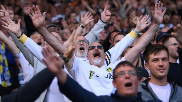 Leeds United fans singing 'Marching on Together' with arms aloft