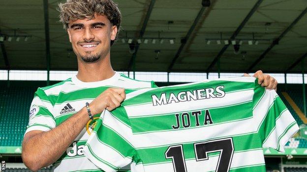 Jota holds up a Celtic shirt after signing