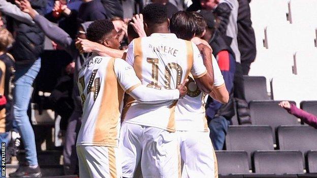 MK Dons celebrate David Wheeler's goal that sealed promotion to League One