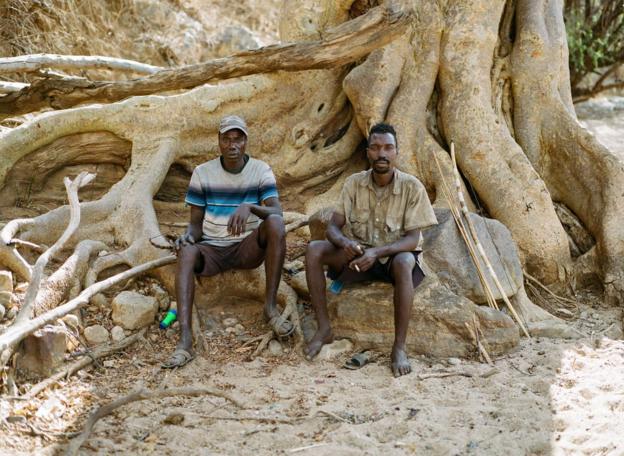 Two Hadza men pose for a portrait with their hunting equipment