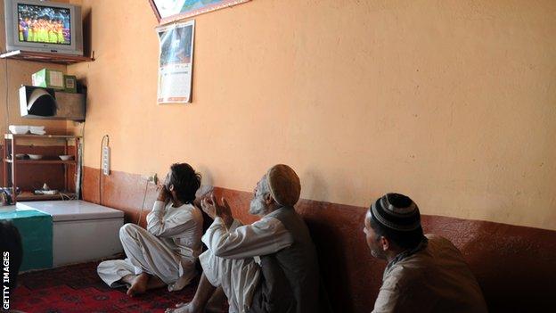 A group of Afghan men watch a match against Pakistan on a television screen in 2013