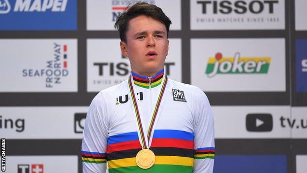Britain's Tom Pidcock stands on the podium wearing a gold medal and the rainbow jersey after winning the 2017 junior world time trial championship