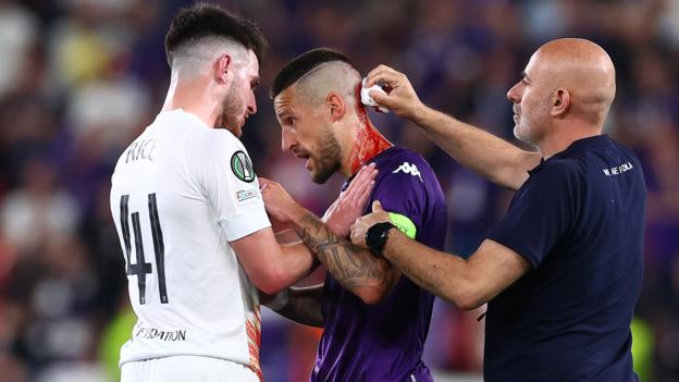 Cristiano Biraghi of Fiorentina receives treatment for a head wound after being struck by an object thrown from the crowd