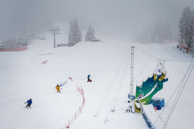 Officials clear the alpine championship course at Cortina after heavy snowfalls delayed the competition.
