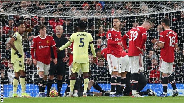 Players wait for a decision on the opening goal as David de Gea receives treatment