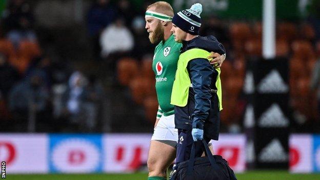 Jeremy Loughman is helped off the pitch by an Irish team medic