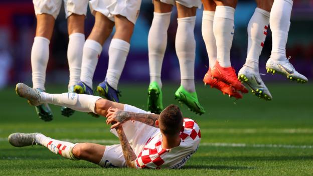 Marcelo Brozovic of Croatia lies on the pitch with his back to play to defend a free-kick as his team-mates in the wall jump