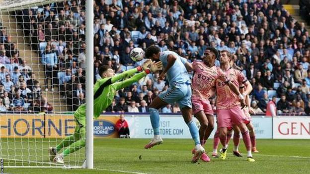 Ellis Simms of Coventry heads beyond Leeds goalkeeper Illan Meslier