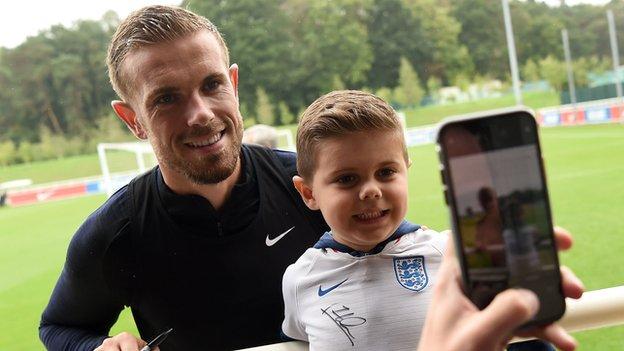 Jordan Henderson poses for a photo with a young England fan