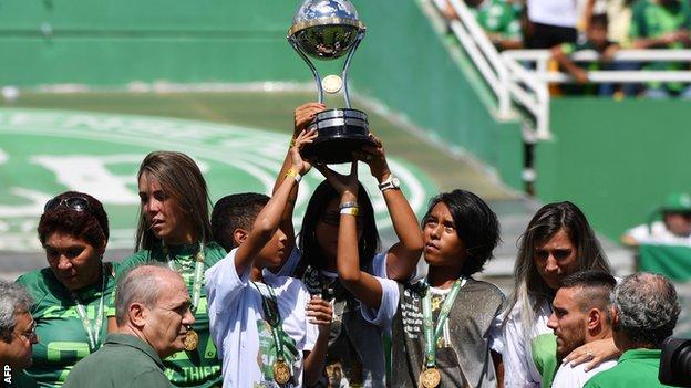 Relatives of the victims lift the trophy