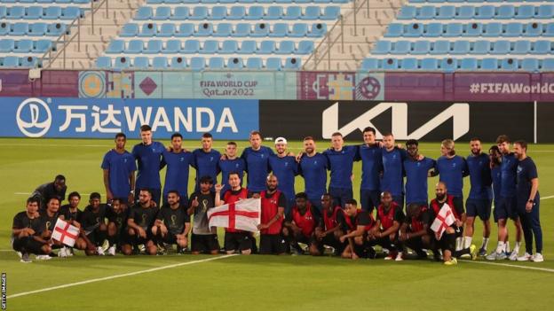 England players have a team photograph with migrant workers
